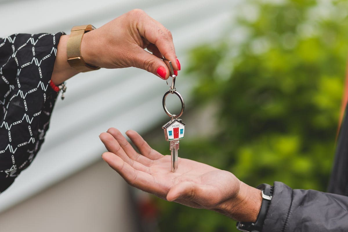 One person passing a house-shaped keyring into another's open palm