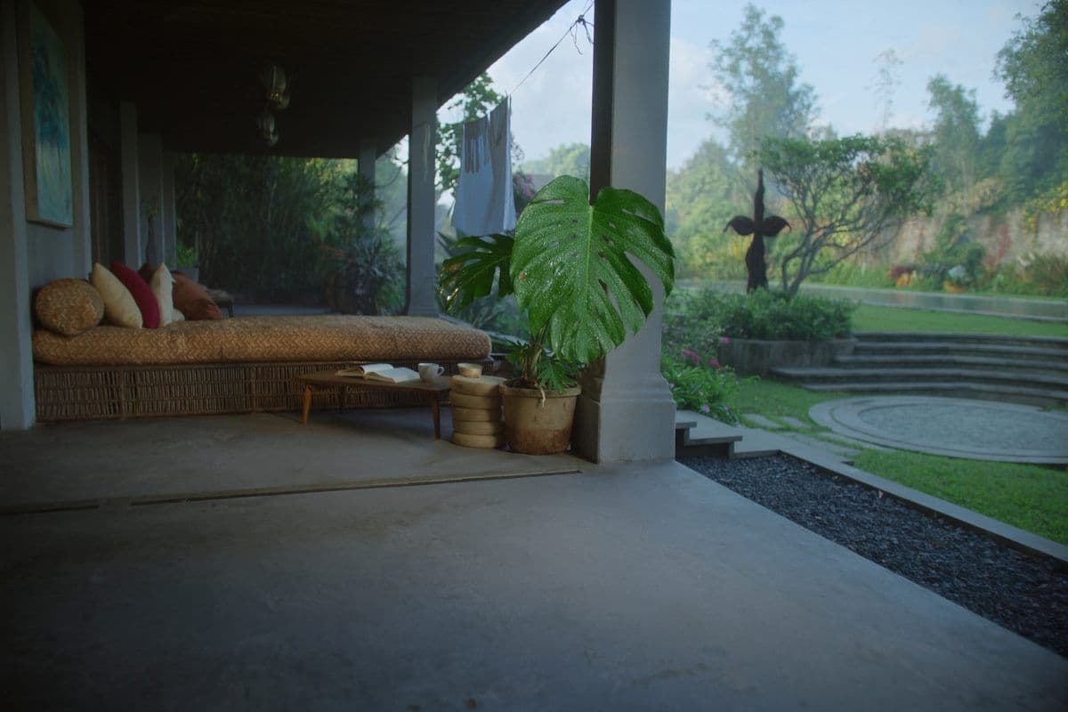 Covered terrace with a cushioned daybed looking onto a lawn and garden