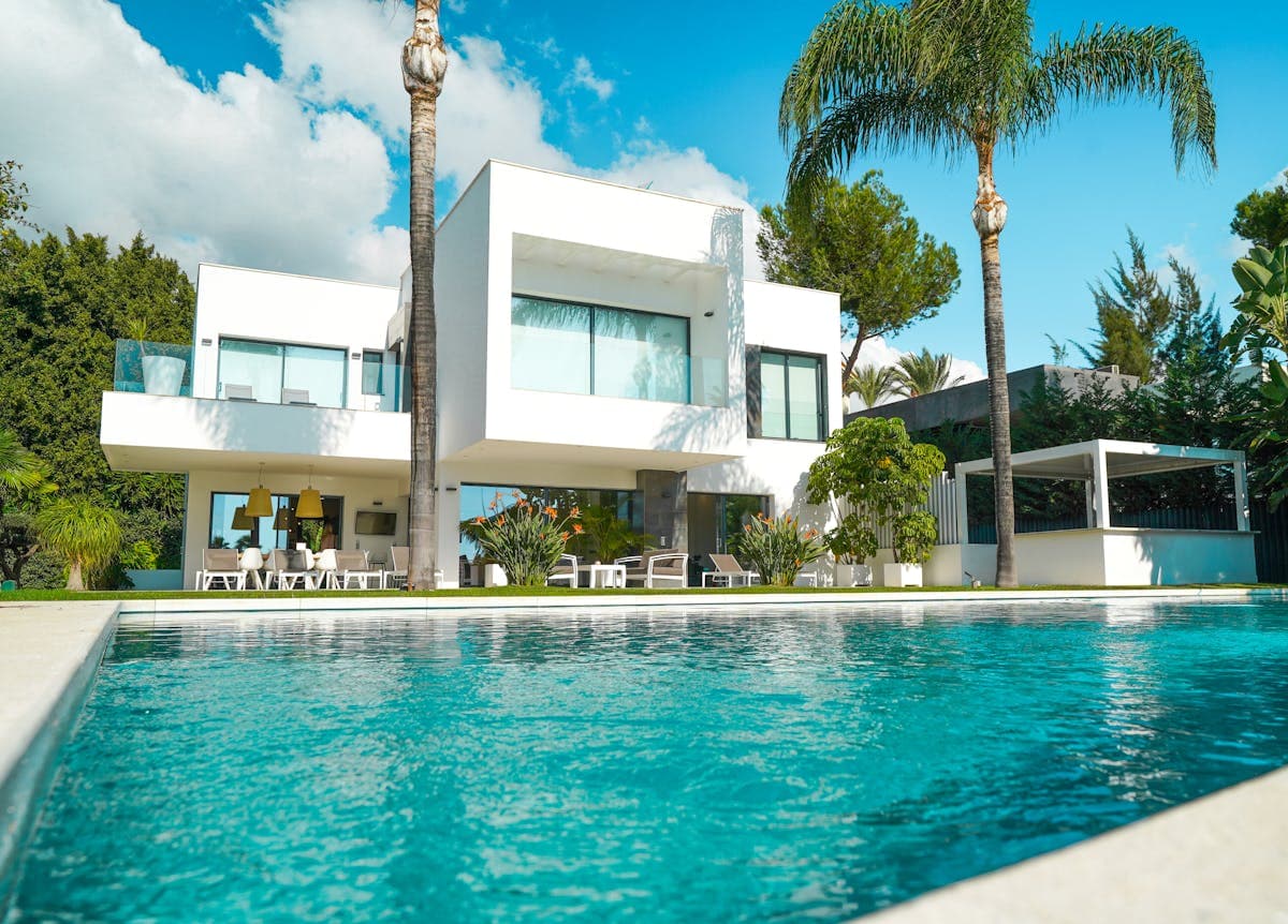 Modern villa with pool in sunlit tropical garden surrounded by greenery